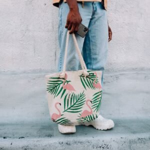 Man in casual attire holding a flamingo print shopping bag, showcasing trendy design.